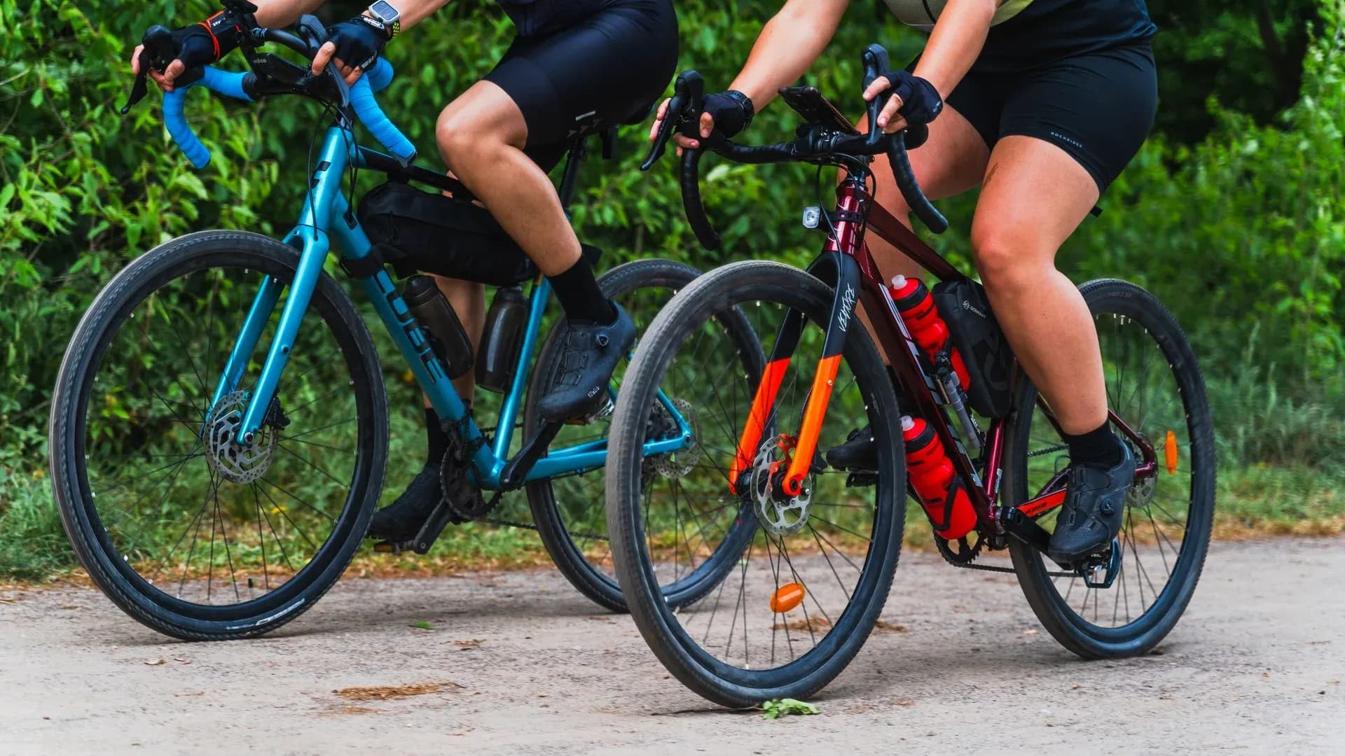 Två cyklister på gravelcyklar längs en grusväg